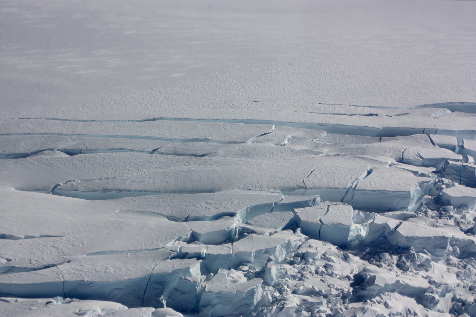 Close-up of deeply cracked blue glacier ice
